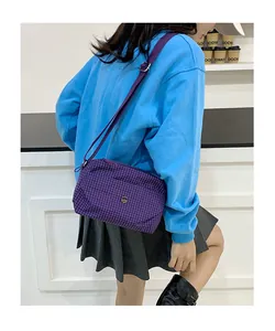 Détail du sac bandoulière en toile à carreaux violets avec bandoulière réglable et logo