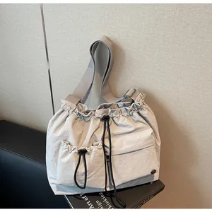 Detail of light gray nylon crossbody bag showing the drawstring design and fabric texture