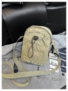 Détail du sac bandoulière en nylon vert olive avec cordon de serrage et broderie