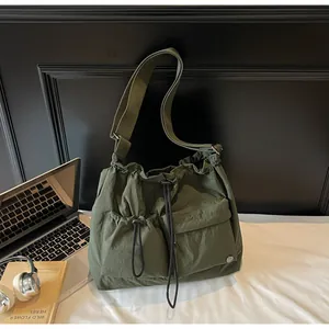 Detail view of olive nylon hobo bag featuring drawstring pockets and wide shoulder strap