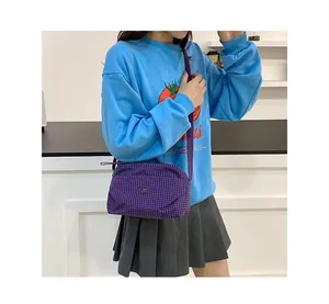 Vue détaillée du sac bandoulière en toile à carreaux violets avec sangle et fermeture