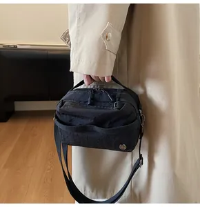 Detail showing the textured waterproof nylon material and dual zippers of this black bag