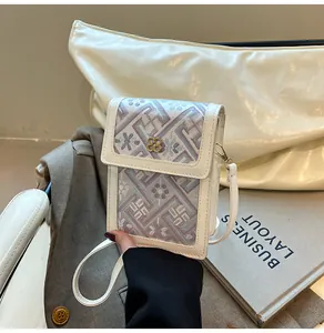 Detail of embroidered floral pattern on a mini crossbody bag with a clover clasp