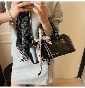 Detalle del bolso Boston negro brillante con cintas de encaje y lazo de cuadros