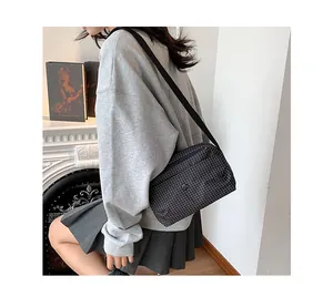 Détail du sac bandoulière en toile à carreaux avec logo en métal et large bandoulière