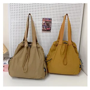 Detail van nylon shopper tassen met trekkoord in beige en geel aan een gaatjesbord