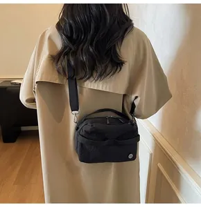 Detail view of the black crossbody bag showing its durable nylon fabric and metal hooks