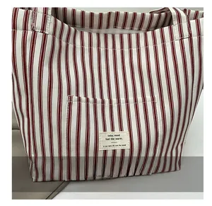 Detail der rot-weiß gestreiften Canvas-Tasche mit Außentasche und gewebtem Etikett-Dekor