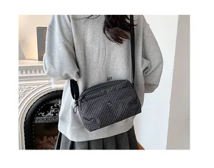 Vue détaillée du sac bandoulière en toile à carreaux noir et blanc avec sangle réglable