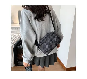 Détail de la bandoulière réglable et du motif à carreaux noirs sur le sac en toile