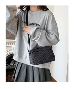 Détail d'un sac bandoulière en toile à damier noir et blanc avec sangle sur mannequin