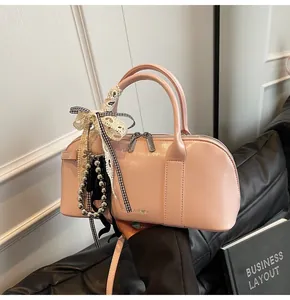 Detalle del bolso rosa claro con lazo de encaje, borla de cuentas y logo CINARO♥K