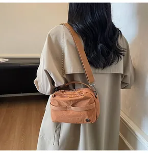Detail view of stylish tan nylon crossbody bag with wide fabric strap on a female model