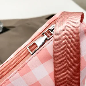 Detail of high-quality smooth silver metal zipper on pink plaid underarm shoulder bag