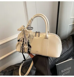 Detalle de bolso de cuero charol blanco con lazo de encaje y adornos en el asa