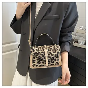 Detailed view of leopard print crossbody bag with beige leather trim and gold metal clasp