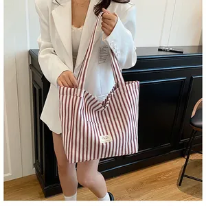 Detail of large canvas tote bag with burgundy stripes, front pocket and durable handles