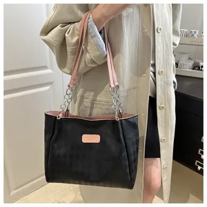 Close-up of black checkered tote bag with pink shoulder straps and silver chain detail