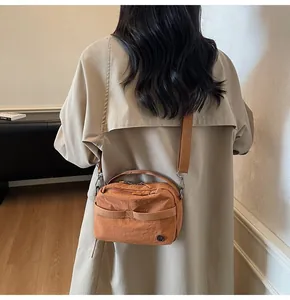 Detail of adjustable shoulder strap and nylon texture on a stylish tan crossbody bag