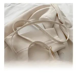 Détail d'un sac bandoulière beige avec sangle réglable et mousqueton doré clair