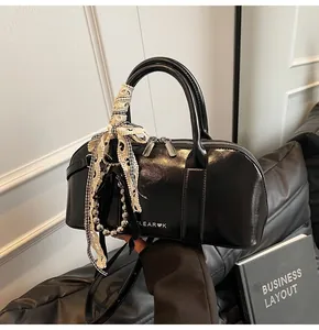 Detalle del bolso Boston negro brillante con lazos de encaje y cadena de cuentas de plata