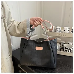 Close-up of black quilted leather tote bag with pink straps and silver chain detail
