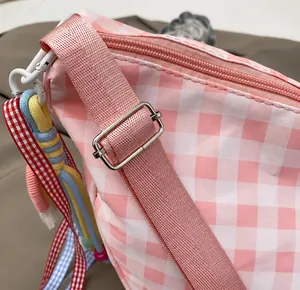 Detail of adjustable pink strap with silver metal buckle on a plaid shoulder bag