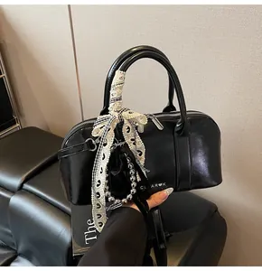 Detalle del bolso Boston negro con lazo de encaje blanco y perla con logo CLEAROK