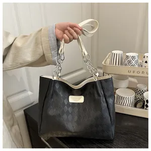 Detail of black quilted leather tote bag with silver chain straps and brand emblem