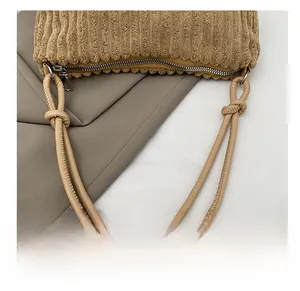 Close-up of corduroy tote bag showing knotted leather strap and smooth metal zipper