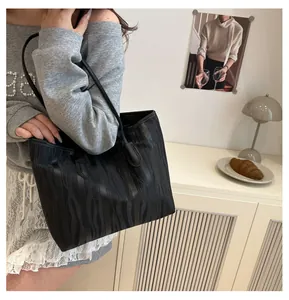 Detail of black tote bag featuring vertical wavy texture and sleek shoulder straps