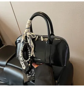 Detalle del bolso acolchado negro brillante con cremalleras plateadas y lazo de encaje