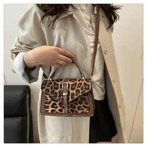 Close-up of leopard print shoulder bag with brown leather trim and golden buckle detail