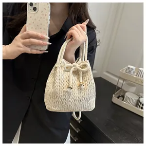 Dettaglio di borsa a secchiello in paglia intrecciata con finiture dorate e lacci