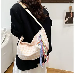 Detail of plaid canvas crossbody bag featuring rainbow charm and star heart embroidery