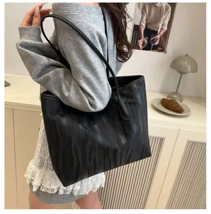 Close-up of a black tote bag with vertical stripes shown on a woman's shoulder