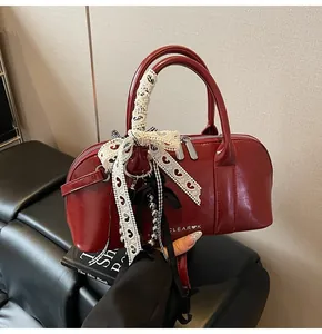 Detalle de bolso de hombro rojo brillante con cinta de encaje y colgante de corazón metálico