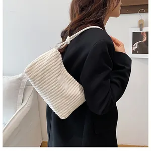 Detail of white corduroy tote bag with woven shoulder strap shown on a model