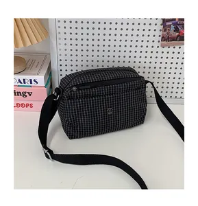 Détail de la sacoche en toile à carreaux avec zips argentés et bandoulière large