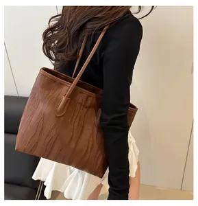 Detail of caramel brown tote bag featuring wavy texture and long shoulder straps