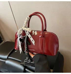 Detalle de bolso rojo oscuro de piel brillante con cinta de encaje y lazo decorativo