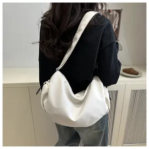 Minimalist white nylon crescent bag shown worn as a crossbody bag on a female model
