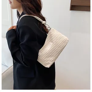 Detail of off-white corduroy shoulder bag showing vertical texture and knotted strap