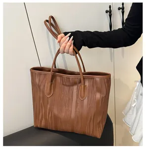 Close-up of caramel brown tote bag with 3D wave texture and soft leather handles