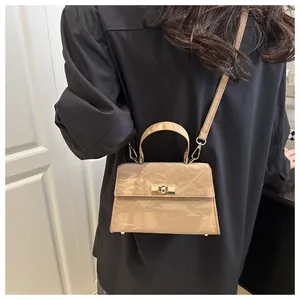 Détail du sac bandoulière en cuir verni crème avec fermoir rotatif en métal doré