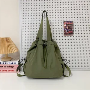 Olijfgroene nylon shopper met trekkoord opgehangen in een minimalistisch decor