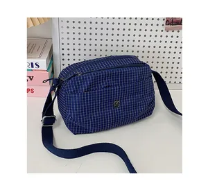 Détail du sac bandoulière en toile à carreaux bleus avec poches zippées et sangle réglable