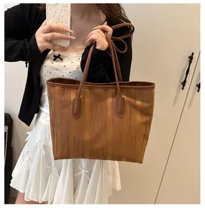 Close-up of brown tote bag featuring wavy wood grain texture and long leather straps