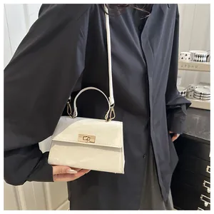Détail du sac bandoulière blanc crème avec fermoir rotatif doré et surface texturée élégante