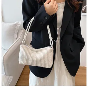 Close-up of white corduroy tote bag showing soft ribbed texture and slim shoulder strap
